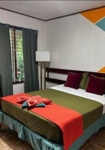a bedroom with a bed with a red blanket on it at Cabinas Palmer Cahuita in Cahuita