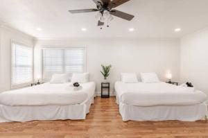 two beds in a white room with a ceiling fan at CA3 House Spacious SoCal Home for Groups in La Palma