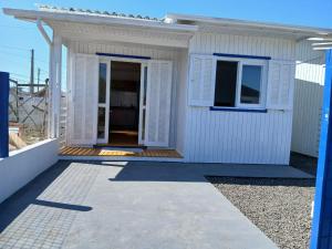 a small white house with a door and a balcony at Casa Mar2 in Balneário Gaivotas +4 photos