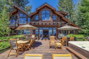 una casa di tronchi con terrazza arredata con tavoli e sedie. di Beyond the Blue Lakefront Escape by Tahoe Getaways - Pet-Friendly 6BR with Pier, Buoy & Hot Tub a Tahoe Marina Estates