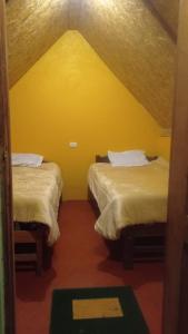 two beds in a room with a yellow wall at Yawar inka ayllu challhuay in Colcapampa +6 photos