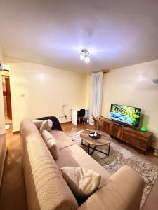 a living room with a couch and a flat screen tv at Zoe Homes-Chic one bedroom near two rivers mall village Marke UN and Embassies along Limuru rd in Ruaka