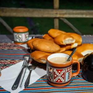 a table with a cup of coffee and some bagels at Yawar inka ayllu challhuay in Colcapampa
