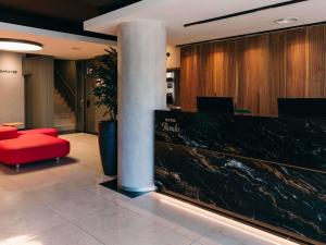 a lobby with a red chair and a column in a building at Ibis Styles Figueres Ronda in Figueres