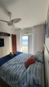 a bedroom with a large bed with a large window at Apartamento com Prédio Frente Mar in Praia Grande
