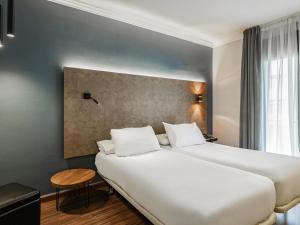 Cette chambre comprend un grand lit blanc et une table. dans l'établissement Ibis Styles Figueres Ronda, à Figueres 126 autres photos