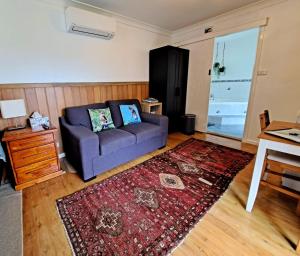 Una sala de estar con un sofá morado y una alfombra roja. en North Durras Beach Cottage, en Durras