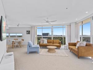 a living room with couches and a table and windows at Stylish 3 Bedroom Apartment with Pool, Sauna & Gym in Gold Coast