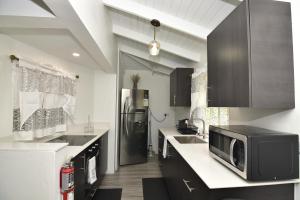 a kitchen with a microwave and a black refrigerator at Good Stay Apartments and Car Rentals in Gros Islet