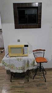 un four micro-ondes assis sur une table à côté d'une chaise dans l'établissement Quarto Solteiro, à Irati