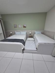 阿拉卡蒂Residencial New Stilo-Coral的配有2张床的客房,铺有白色瓷砖地板