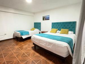 a bedroom with two beds and a blue headboard at Hostal CECIL + in Vallenar