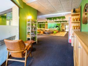une pièce avec des murs verts et une chaise dans un magasin dans l'établissement Ibis Styles Arlon Porte du Luxembourg, à Arlon
