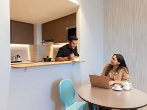 a man and a woman sitting at a table with a laptop at Adagio Jeddah City Center in Jeddah