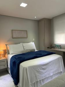 a bedroom with a large bed with a blue blanket at Novo, lazer completo e 3 quadras da Av. Paulista. in Sao Paulo +33 photos