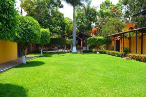 a yard with green grass and trees and a building at Casa Kolping in Tuxtla Gutiérrez