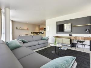 Una sala de estar con un sofá y un televisor en Aparthotel & Spa Adagio Vannes, en Vannes