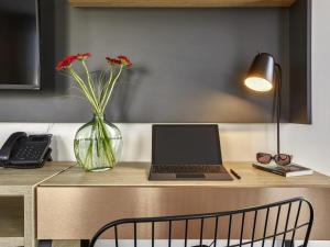 a desk with a laptop and a vase with flowers at Aparthotel & Spa Adagio Vannes in Vannes