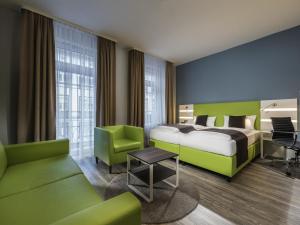 a hotel room with a bed and green furniture at Offenburg City Hotel by Belvilla in Offenburg
