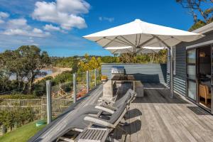 un patio avec une table, des chaises et un parasol dans l'établissement The Cottage - Oneroa's Best Viewpoint, à Waiheke Island