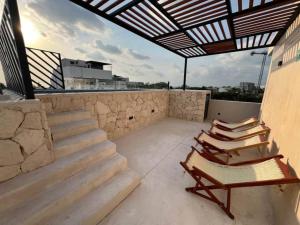a patio with chairs and stairs on a roof at A little slice of paradise in Puerto Morelos