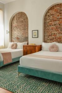 ルイスビルにあるThe Bellwether Hotelのレンガの壁のある部屋にベッドが2つある