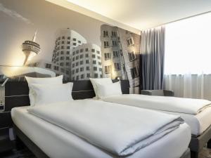 two beds in a hotel room with buildings on the wall at Novotel Duesseldorf Airport in Düsseldorf +69 photos