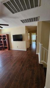 an empty living room with wood floors and a flat screen tv at Spacious 5-bedrm home 3 min from Cardinals Stadium in Phoenix