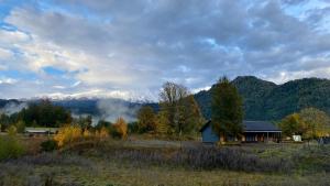 a house in a field with mountains in the background at Casa Huilo Hostal in Panguipulli