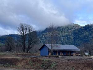 a small blue building in front of a mountain at Casa Huilo Hostal in Panguipulli