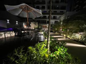 a patio with a table and an umbrella at night at Flat Vert House in João Pessoa