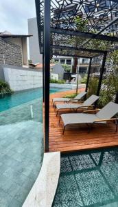a wooden deck with lounge chairs and a swimming pool at Flat Vert House in João Pessoa