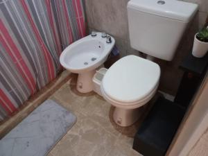 a bathroom with a white toilet and a sink at Elmosquetal in Villa Yacanto +58 photos