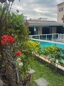 - un jardin avec des fleurs rouges à côté d'une piscine dans l'établissement Aconchego da praia, à Arraial do Cabo 15 autres photos