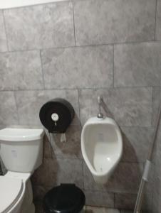 La salle de bains est pourvue de toilettes blanches et d'un urinoir. dans l'établissement hospedaje, à Pozos