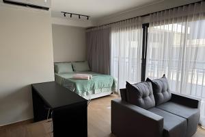 a living room with a couch and a bed and a window at Max Jardim São Paulo in São Paulo