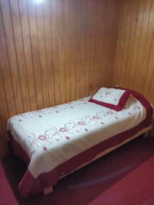 Una cama pequeña con una manta encima. en Cabaña Claudia Espinoza, en Villarrica