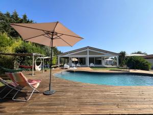 a patio with a chair and an umbrella next to a pool at Casa da Oliveira in Melides
