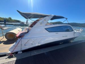 a white boat parked on a dock on the water at Room accommodates up to 5 complete apartment in Mangaratiba
