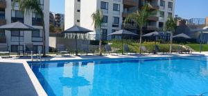 a large swimming pool with chairs and umbrellas at Apartamento tranquilo y familiar in Xochitepec