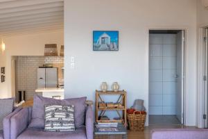 Una sala de estar con un sofá morado y una cocina. en Waikare House - Above Oneroa Bay, en Waiheke Island