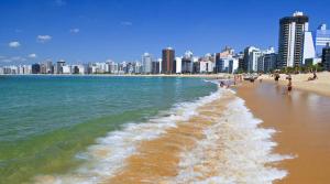 a beach with people and buildings in the background at Apartamento completo, 1 quarto, sala, banheiro em prédio de frente para o mar in Vila Velha