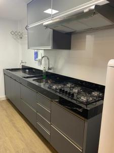 a kitchen with a black counter top and a stove at Apartamento completo, 1 quarto, sala, banheiro em prédio de frente para o mar in Vila Velha
