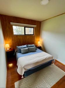Un dormitorio con una cama con dos almohadas y una ventana. en Siempre Verde Cabins, en Puerto Tranquilo