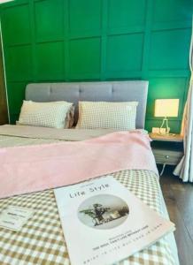 a bed with a book on it with a green wall at Almas Suites Couple Sunrise Netflix 100mbps BySTAY in Nusajaya +50 photos