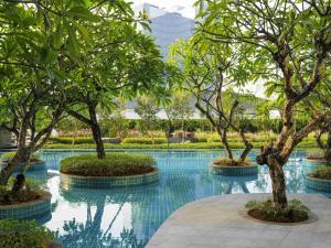 a swimming pool with trees in the middle of it at Swissôtel Jakarta PIK Avenue in Jakarta