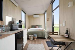 a bedroom with a bed in a room with windows at Crossing Pines by Tiny Away in Beaufort