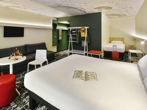Cette chambre comprend une table blanche et un canapé. dans l'établissement Ibis Annecy - Cran-Gevrier, à Annecy
