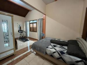 a bedroom with a bed and a room with a treadmill at Villa Sakinah Ciwidey in Bandung