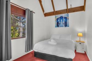 a bedroom with a white bed and a window at Cornwall Cottage in Merimbula